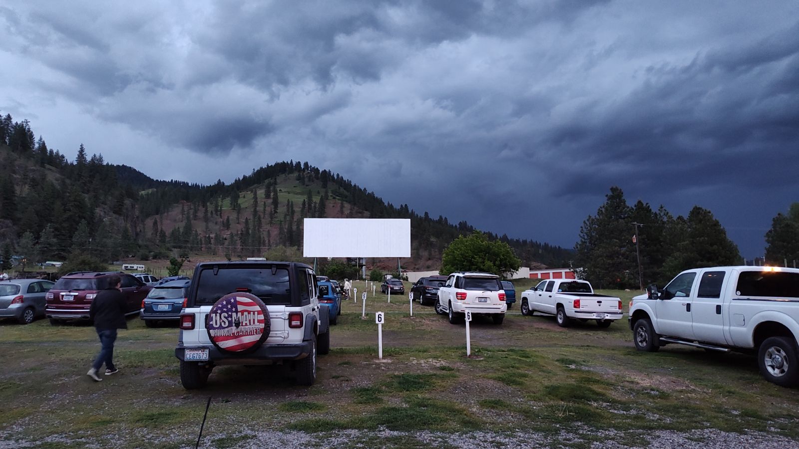 a drive-in theatre with cars parked in front of the screen